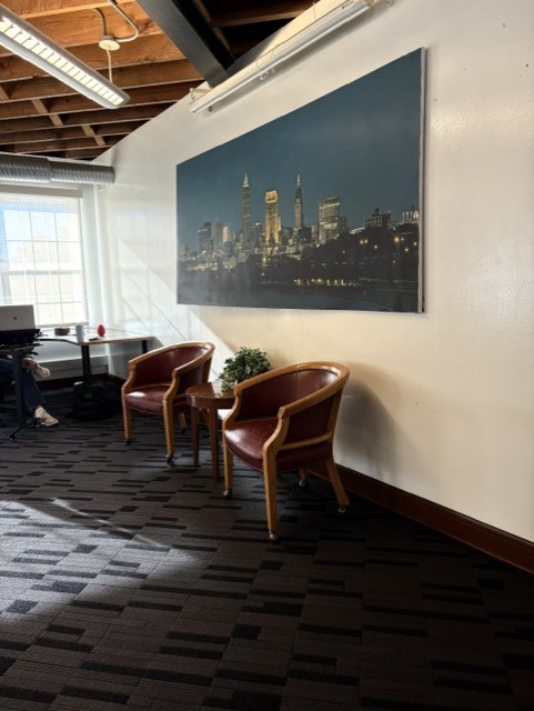 Lounge seating with leather chairs beneath a Cleveland skyline painting